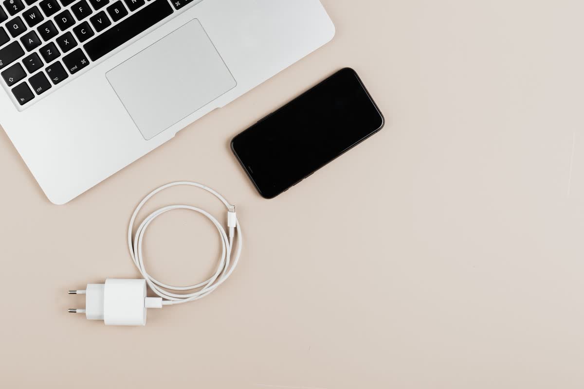 A laptop, phone and charger on a desk