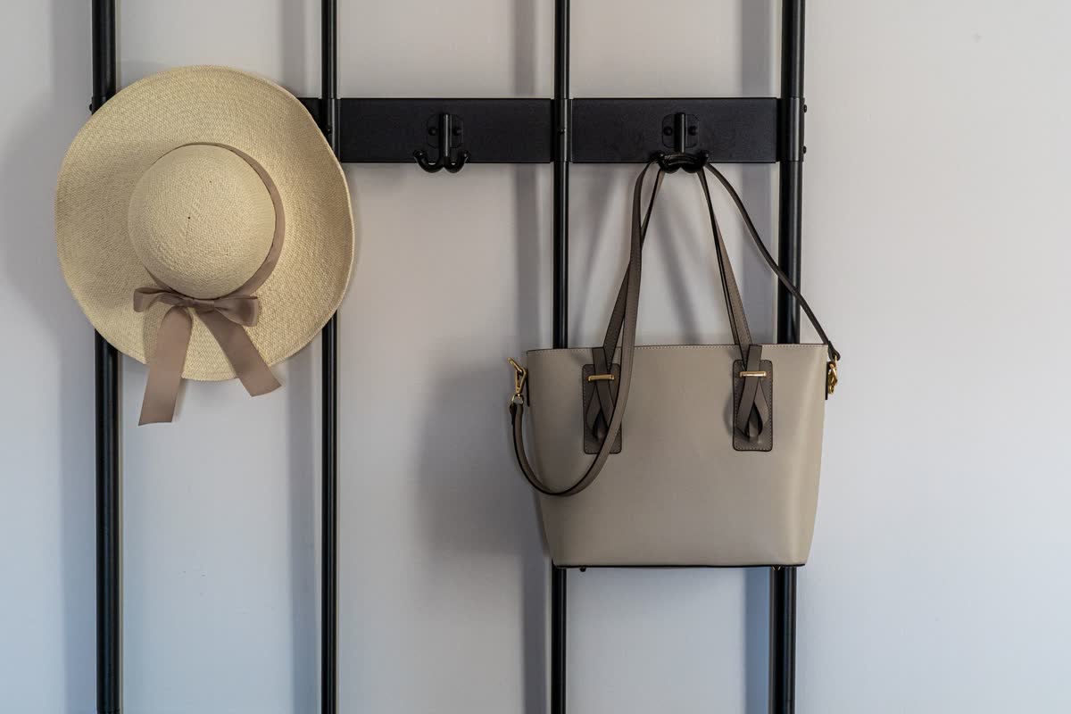 A hat and a bag hanging on wall hooks