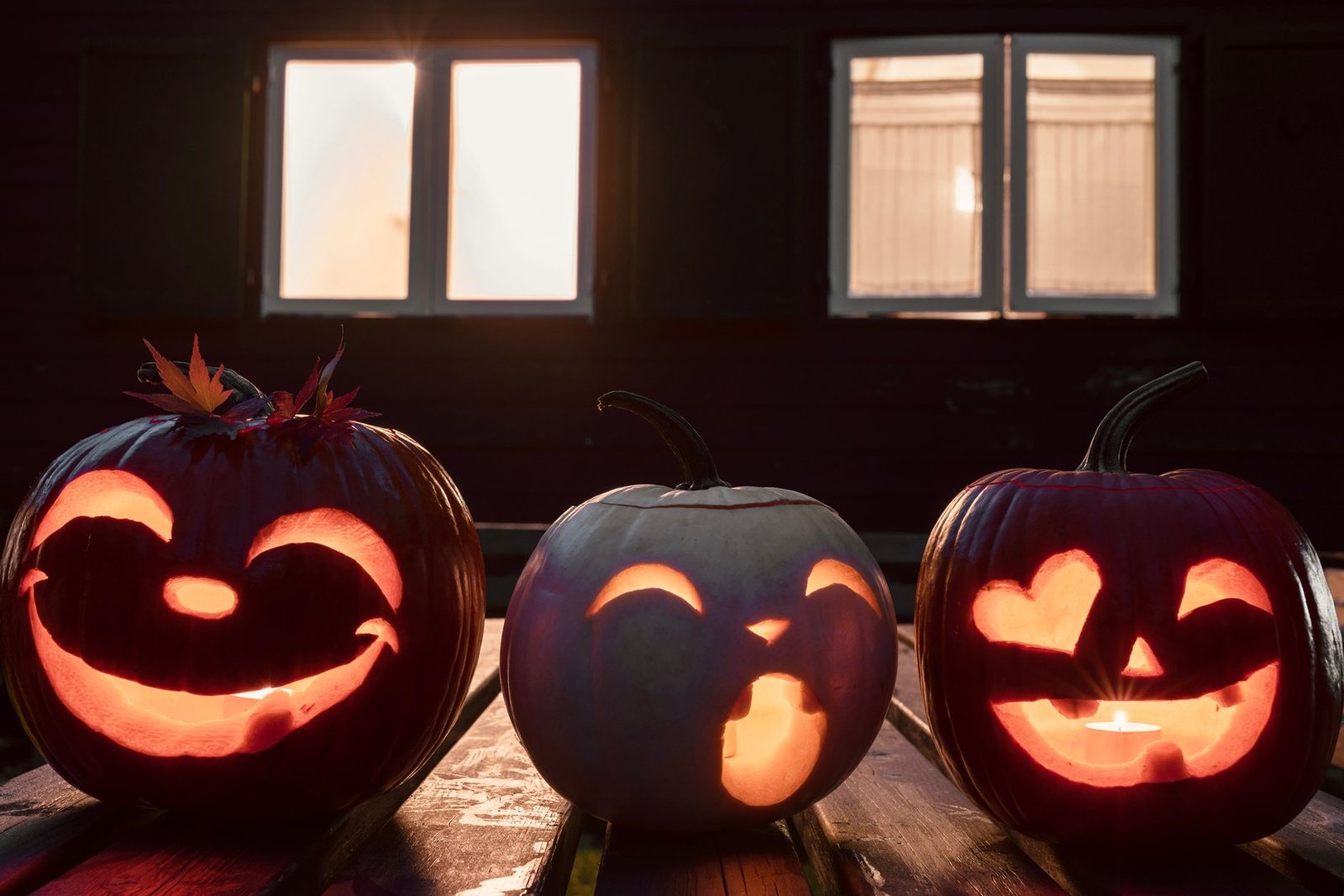 Glowing carved jack-o-lanterns in a row on a porch