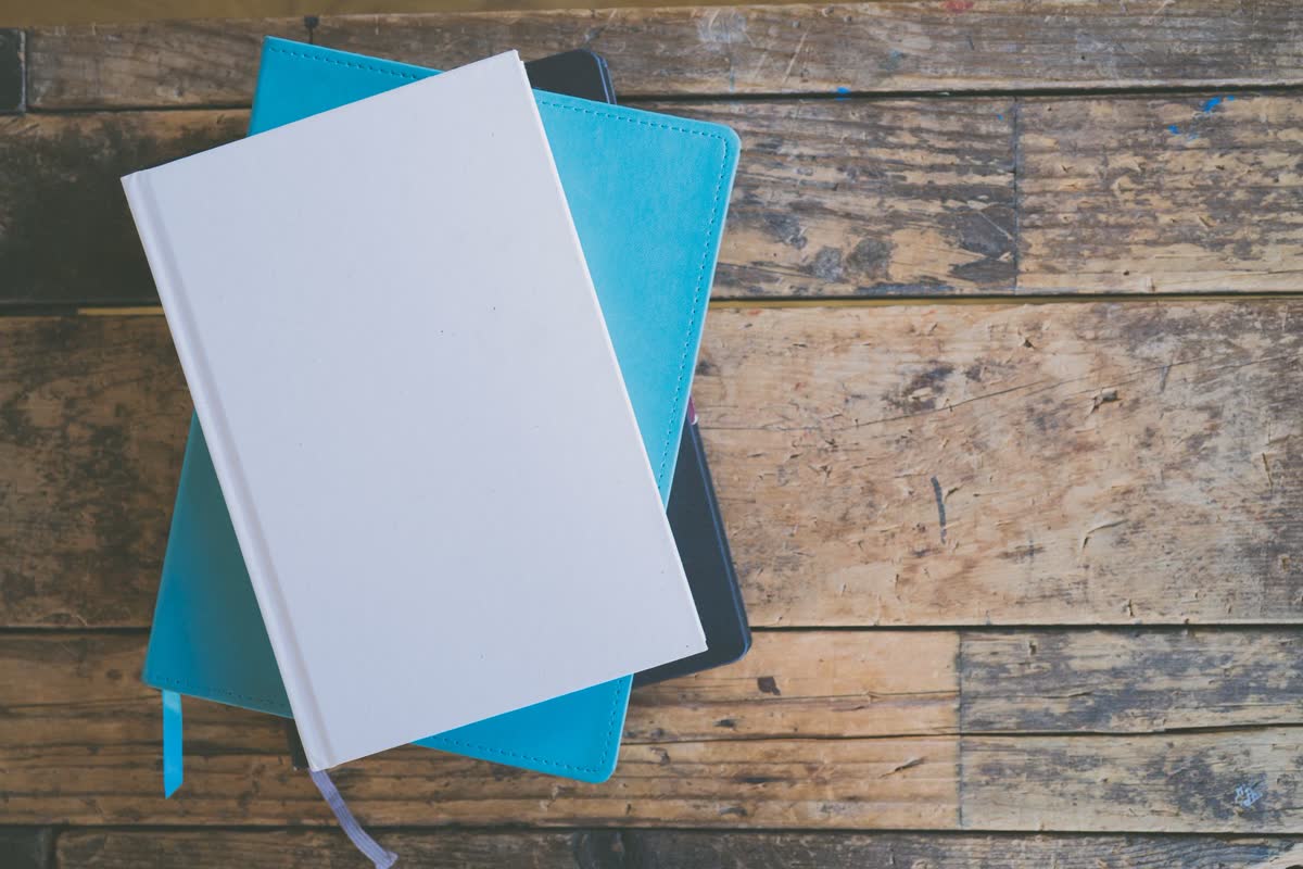 Notebooks stacked on a wood desk