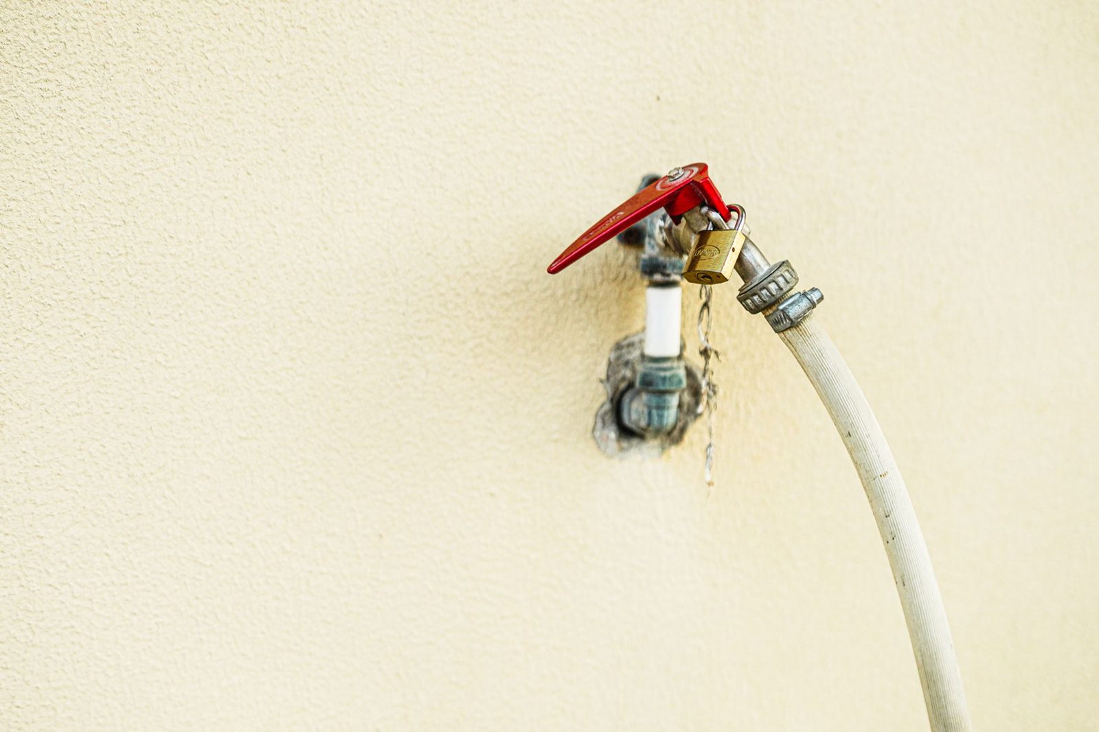 An outdoor faucet spigot on the side of a house