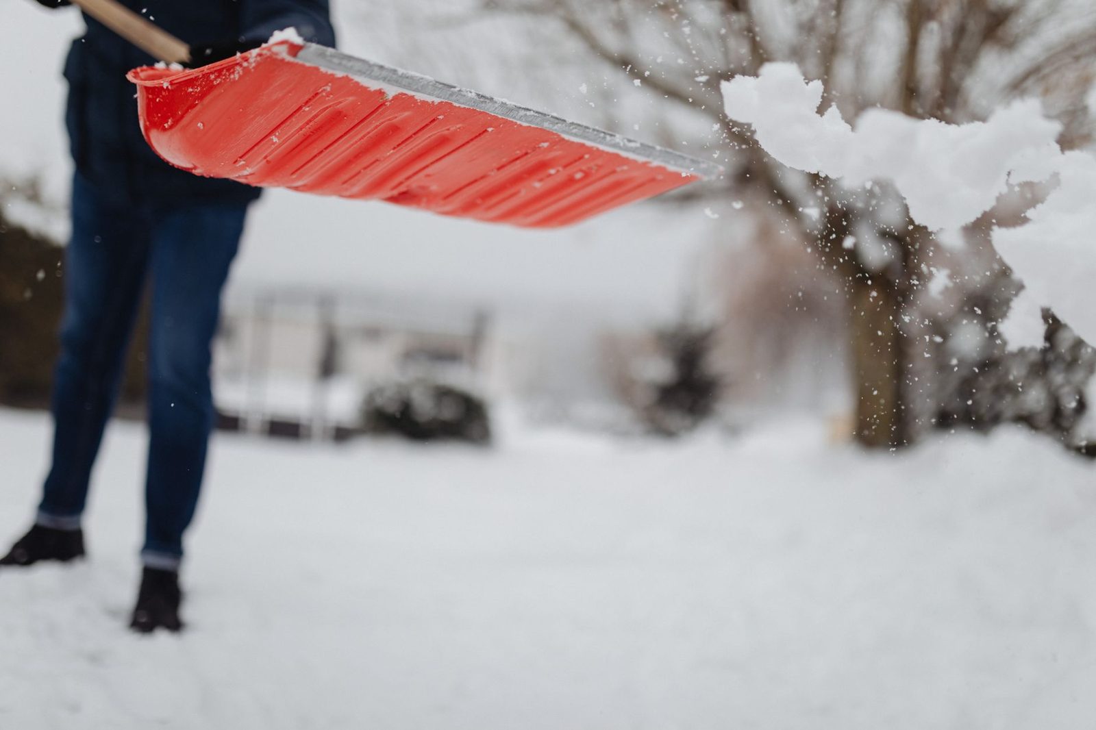 A person shoveling snow with an ergonomic shovel